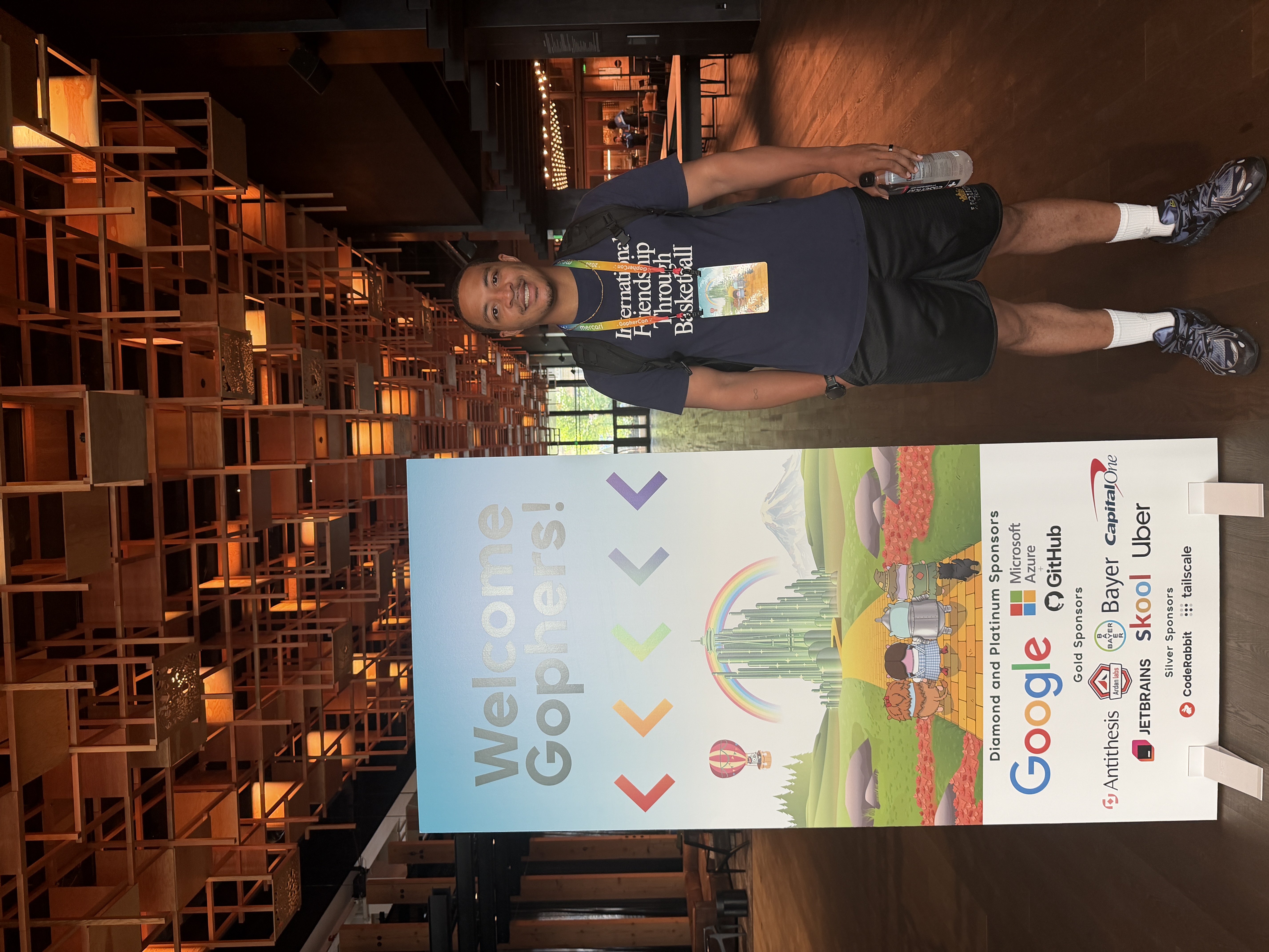 Me standing beside the GopherCon 2026 welcome banner, illustrated with a Wizard of Oz yellow brick road and listing the conference sponsors